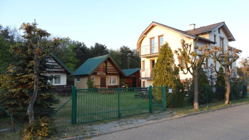 uma casa com uma cerca verde em frente em Domki letniskowe "U Adaska" em Chałupy