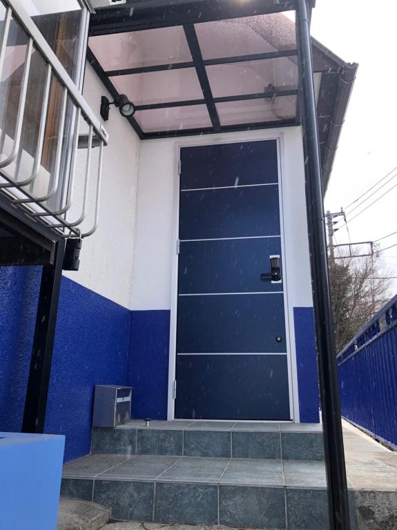 a blue garage door on a building with stairs at Oyado Zen in Kusatsu