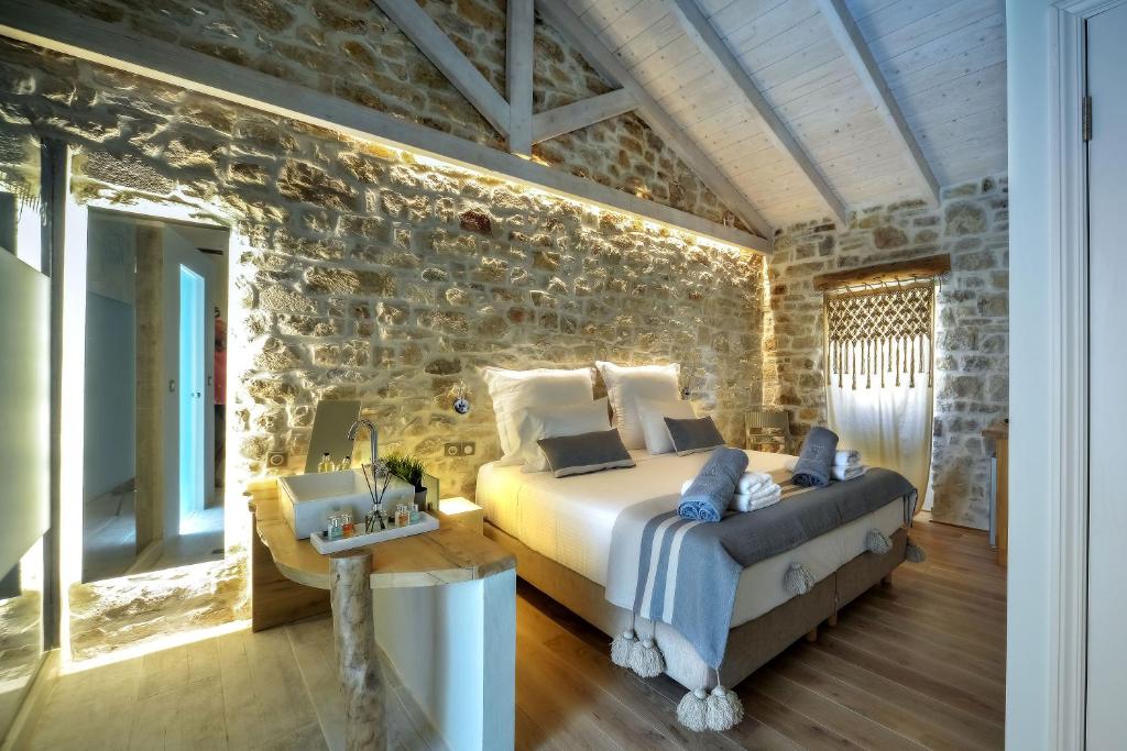 - une chambre avec un lit et un mur en pierre dans l'établissement Paxos Fairytales Lovenest 2, à Gaios