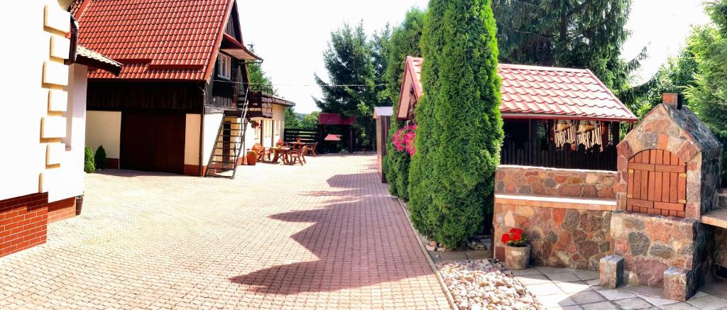 a brick walkway next to a building with a hedge at Pensjonat U Kasi in Węgorzewo
