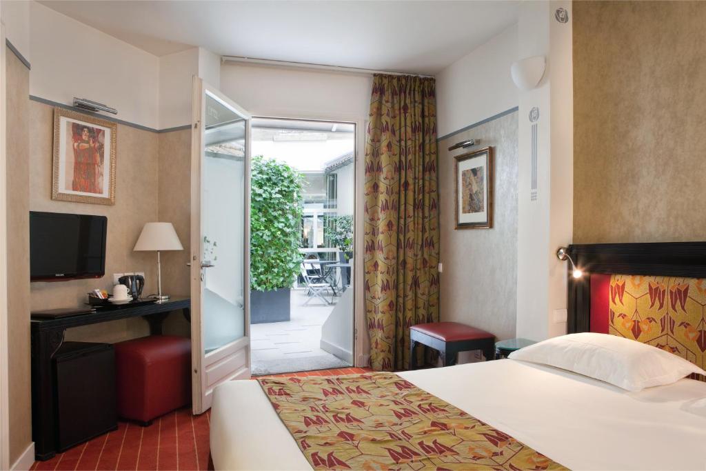 Habitación de hotel con cama y puerta corredera de cristal en Hotel Eiffel Seine, en París