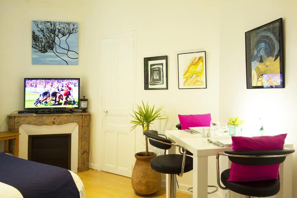 - un salon avec une table, des chaises et une télévision dans l'établissement CANNES - À DEUX PAS DU PALAIS DES FESTIVALS, à Cannes