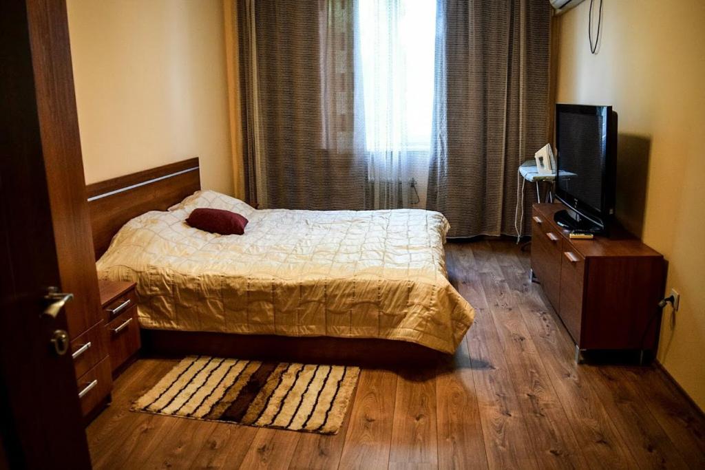 a bedroom with a bed and a flat screen tv at булевард „Демокрация“ Апартамент Златна Рибка in Burgas