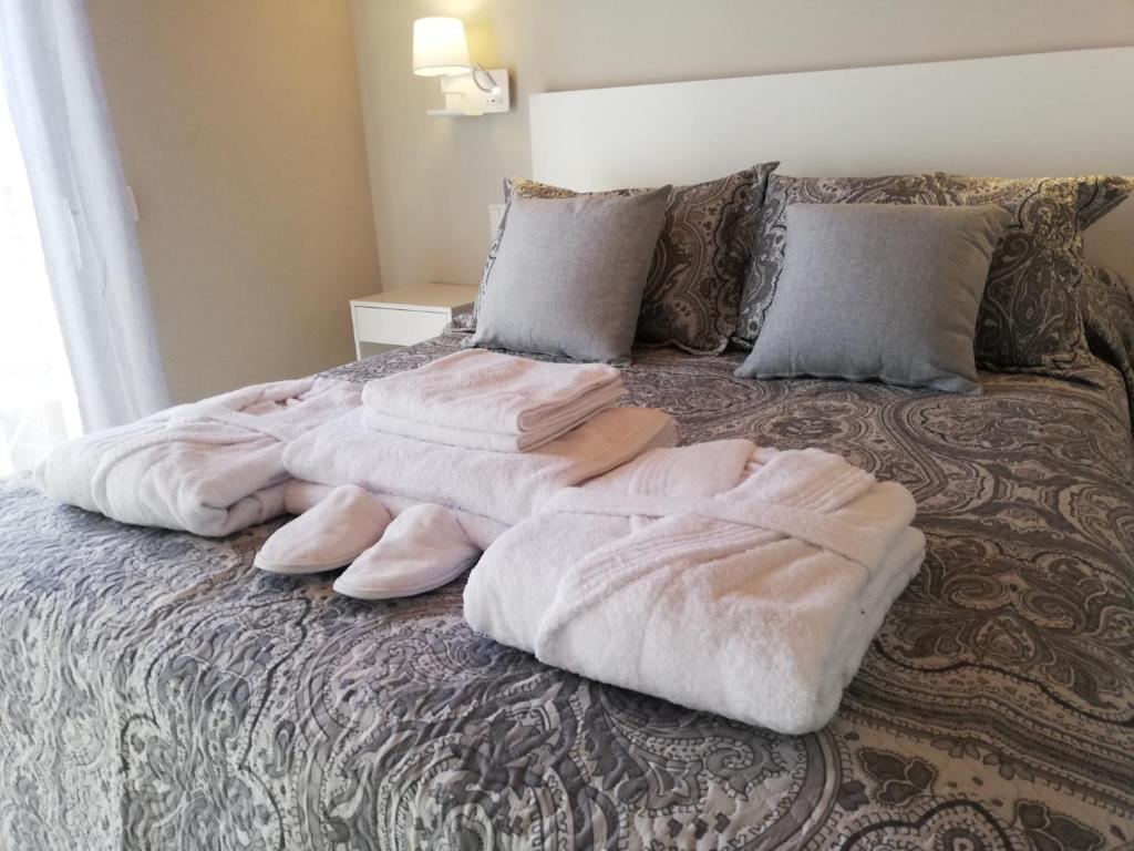 een bed met roze dekens en kussens erop bij Nueva suite jacuzzi relax beach & mountain in Palamós
