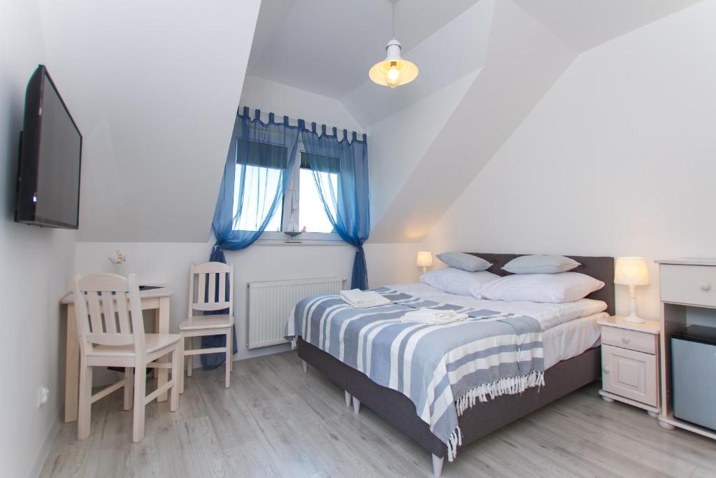 1 dormitorio con 1 cama, escritorio y TV en Willa Rejs en Krynica Morska