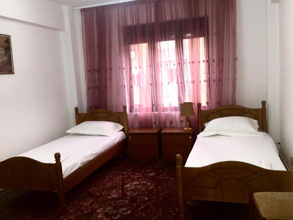 two beds in a small room with a window at Apartament Berati in Berat