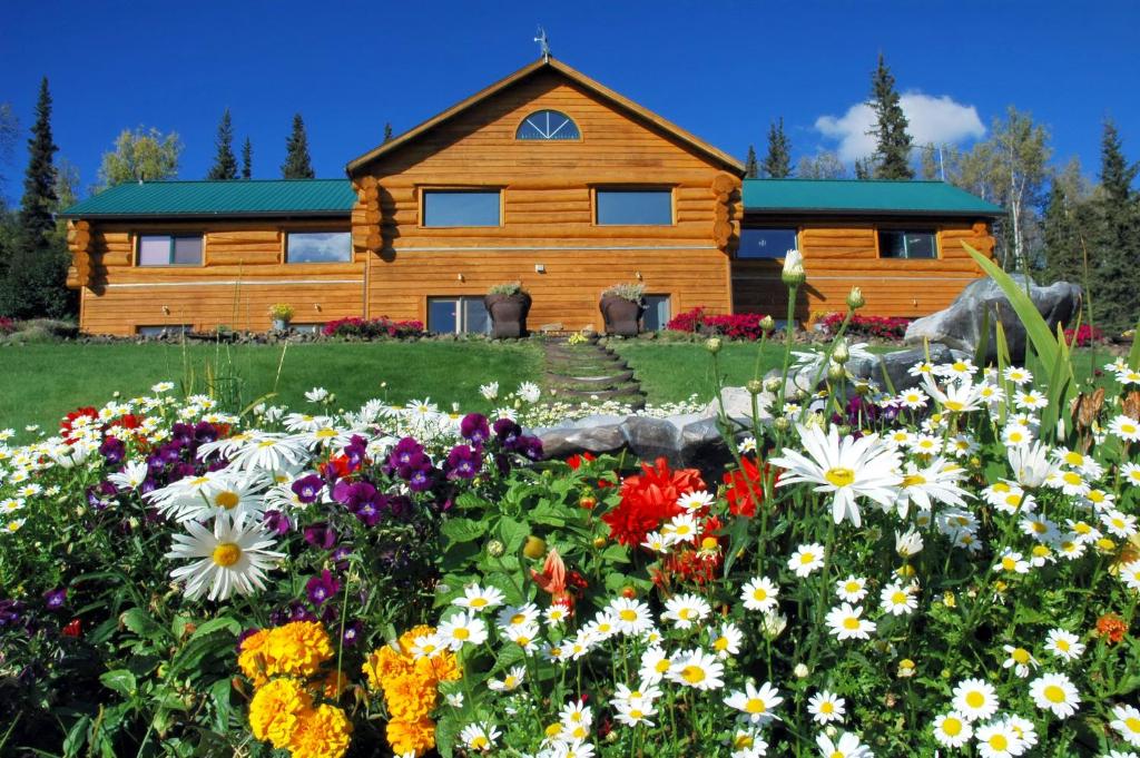 uma cabana de madeira com flores à frente em A Taste of Alaska Lodge em Fairbanks