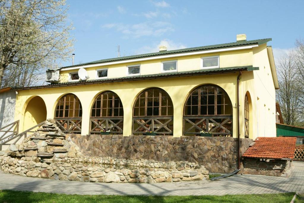 a large building with large windows and a stone wall at Hotel Mlyn in Nikolayev