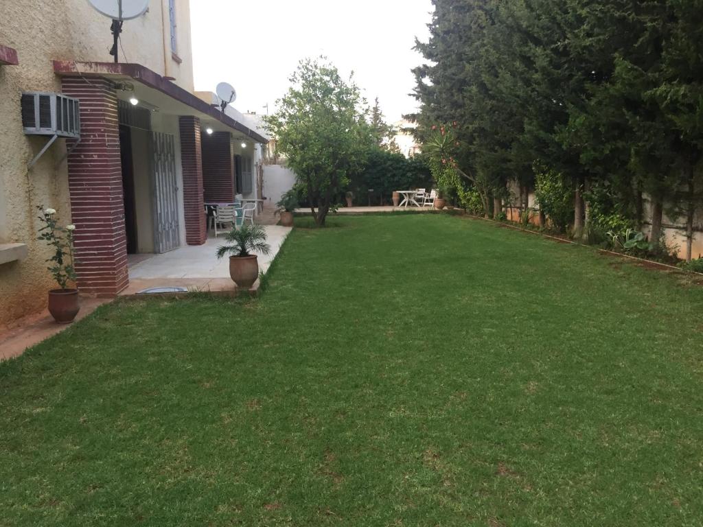 une cour avec de l'herbe verte à côté d'un bâtiment dans l'établissement Villa Tazi, à Meknès