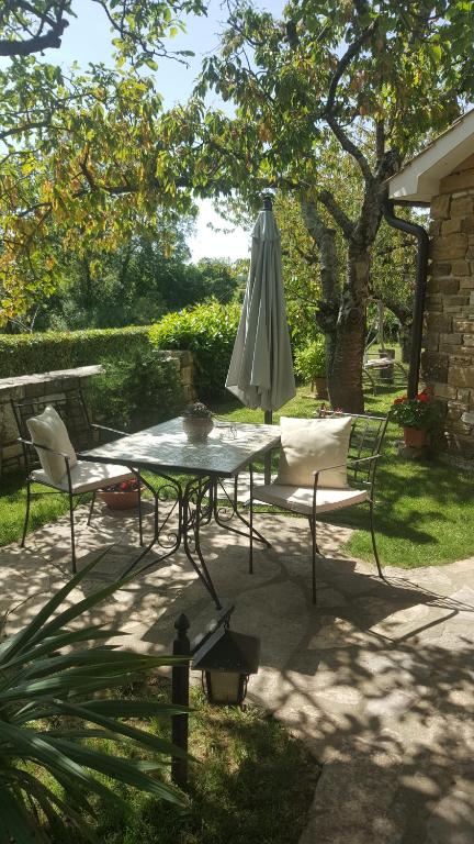 a table and chairs with an umbrella on a patio at Studio apartment Cami - Cottage with a soul in Gračišće