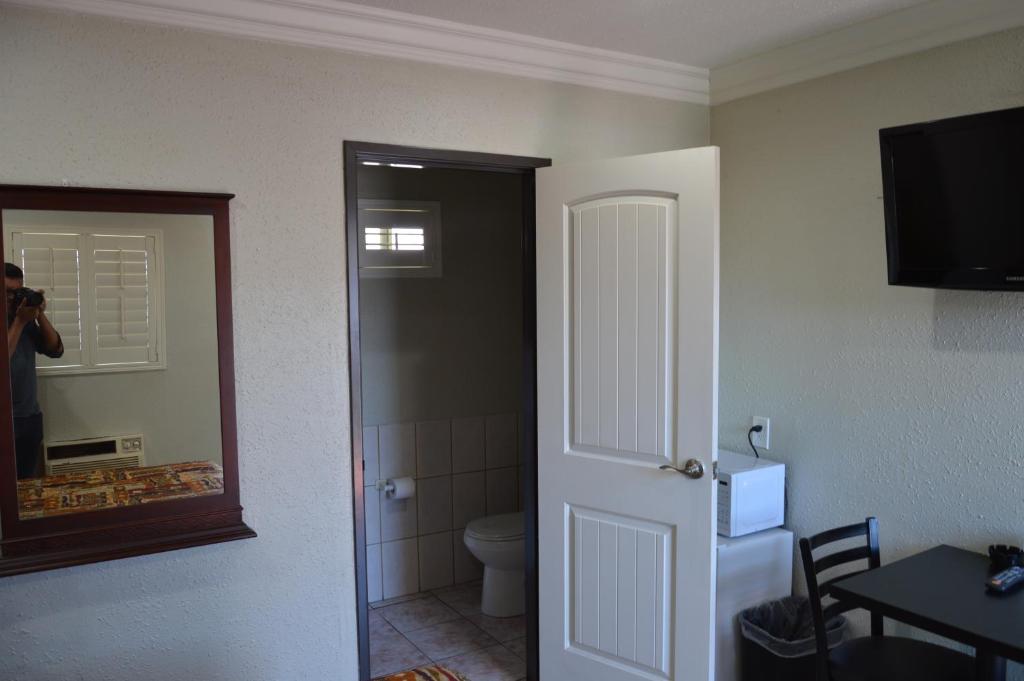 a person taking a picture of a bathroom with a toilet at El Rey Inn in Gardena