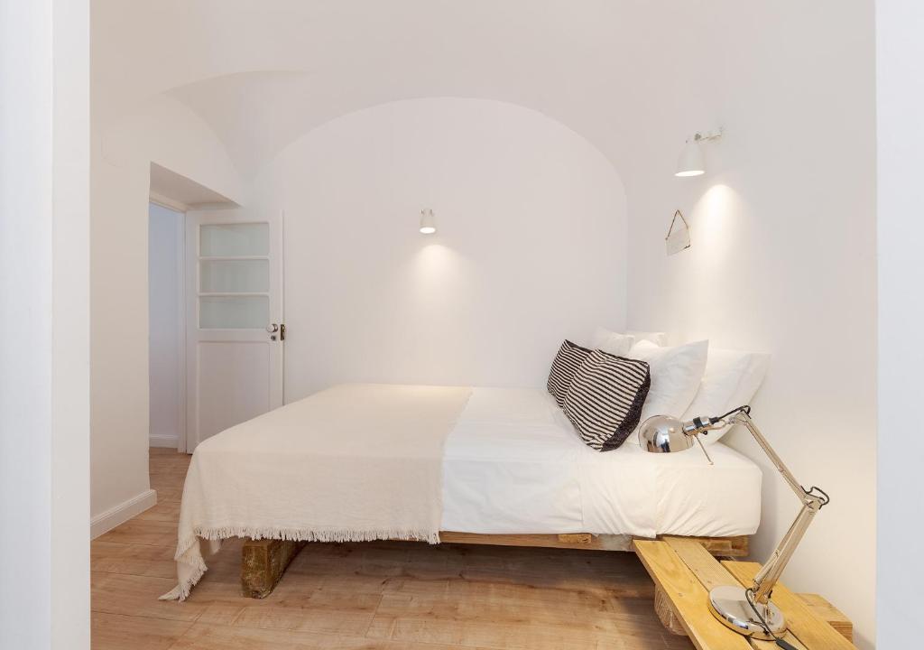 ein weißes Schlafzimmer mit einem Bett und einer Lampe in der Unterkunft Studio Hideaway- in a Traditional Neighborhood in Lissabon