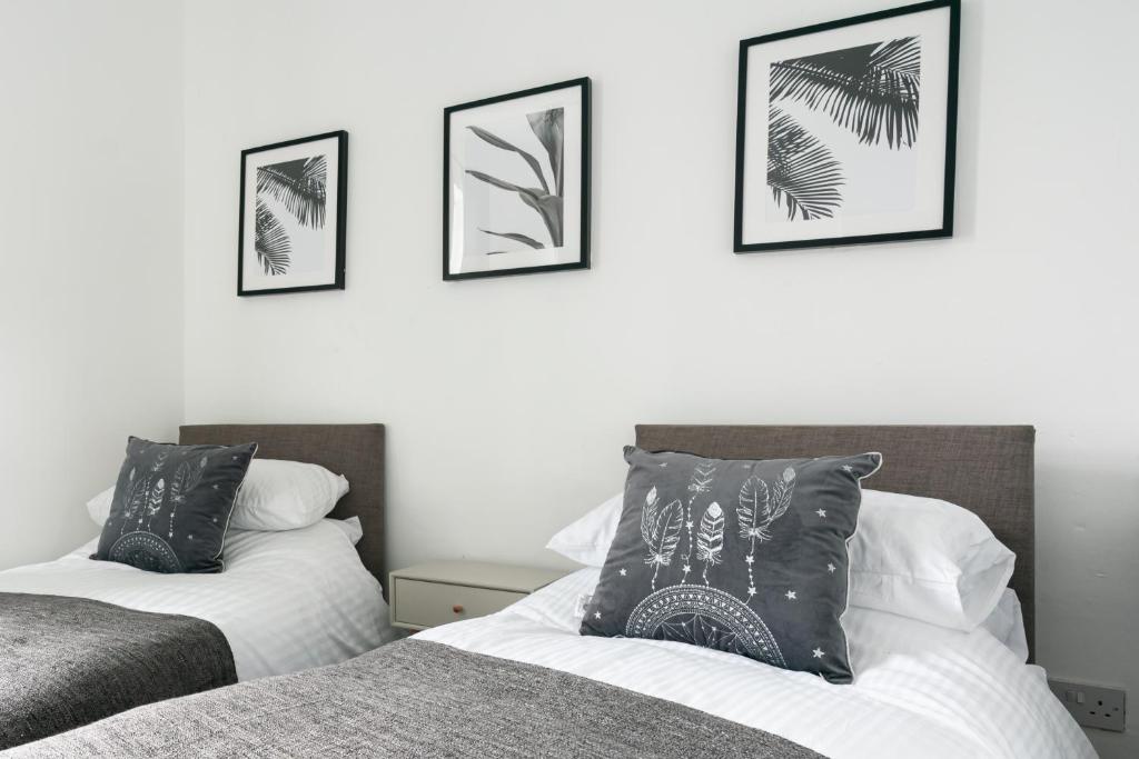 two beds in a bedroom with framed pictures on the wall at Netherfield in Park Gate