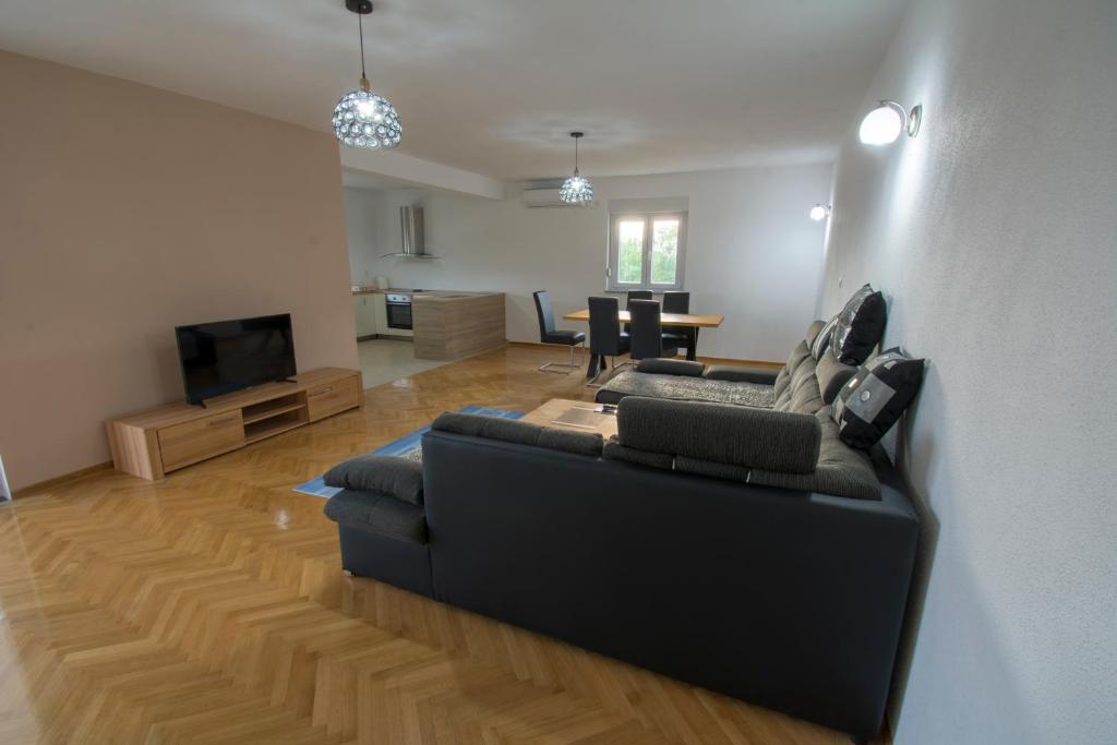 a living room with a black couch and a television at Apartman Vitina in Ljubuški