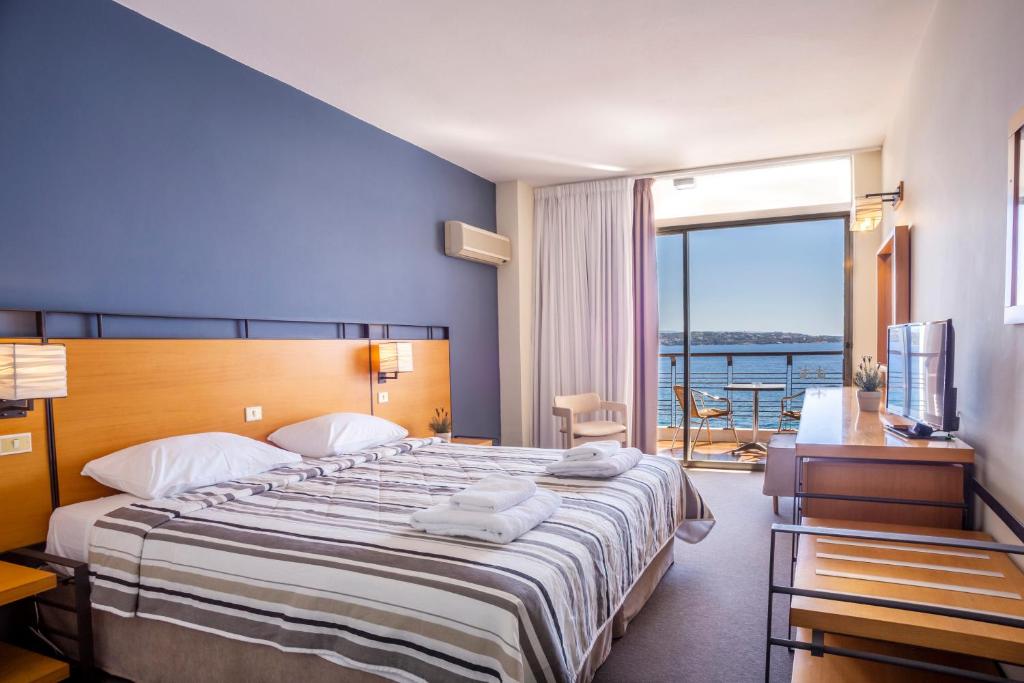 a hotel room with a large bed and a balcony at Spetses Hotel in Spetses