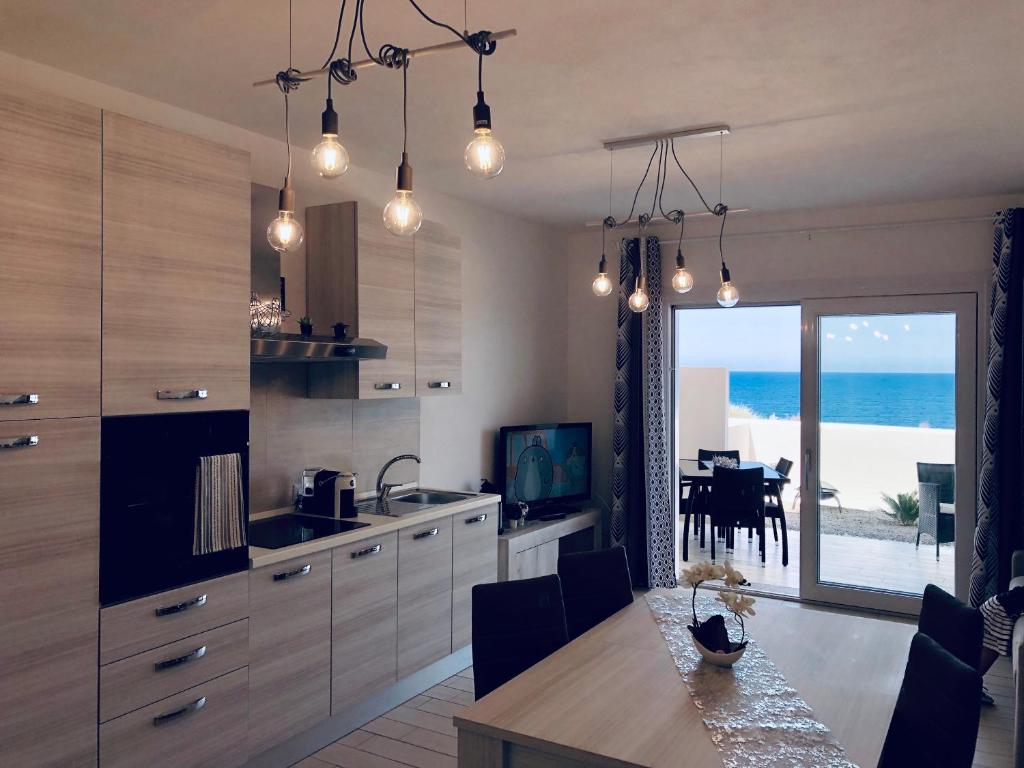 uma cozinha com uma mesa e vista para o oceano em Il Tramonto Luxury House em Valledoria