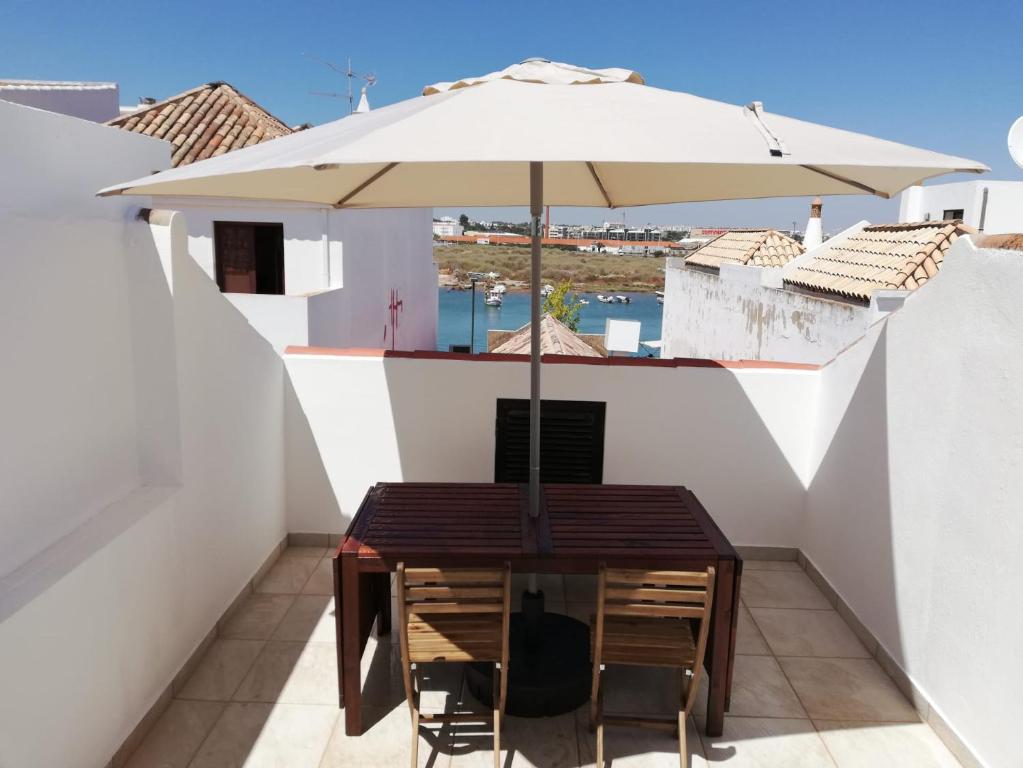 un tavolo con ombrellone su un balcone di Casa do canto a Tavira