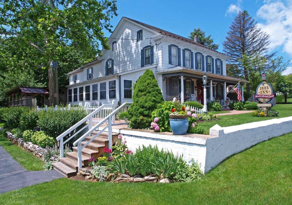 a large white house with a porch and flowers at 1825 Inn Bed and Breakfast in Palmyra