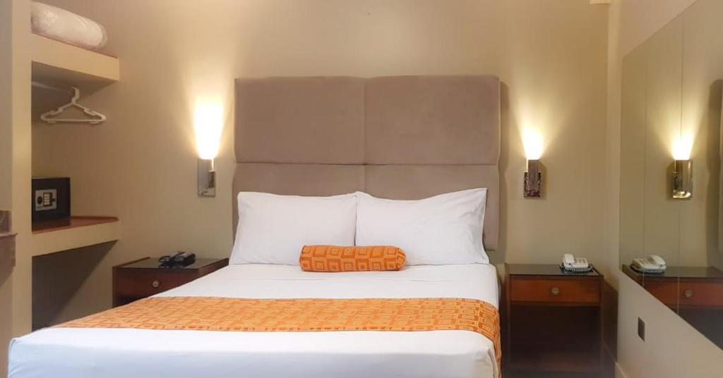 een slaapkamer met een bed met een oranje kussen erop bij Hostal Lince in Lima