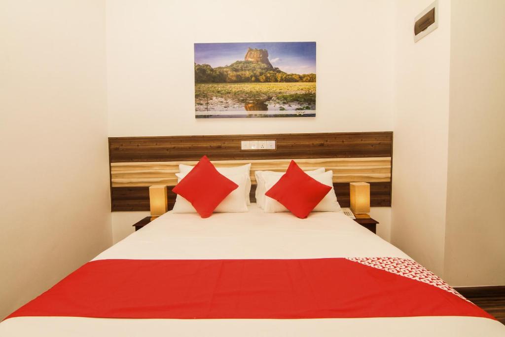 een slaapkamer met een bed met rode kussens en een schilderij bij Clove Transit Hotel in Kotugoda