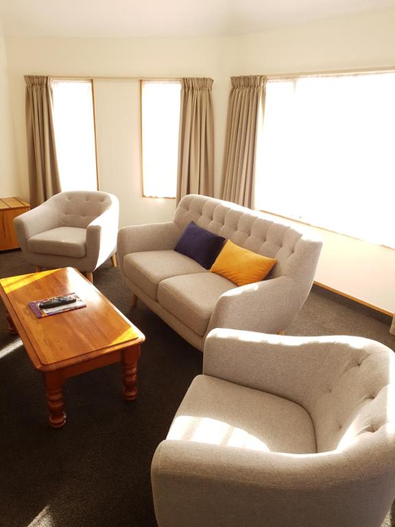 a living room with a couch and two chairs and a table at Fitzherbert Castle Motel in Palmerston North