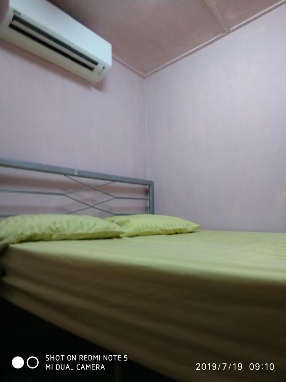 a bedroom with a bed with green sheets at Nora Damin Homestay Kampong Jalan Kebun in Kampong Lombong