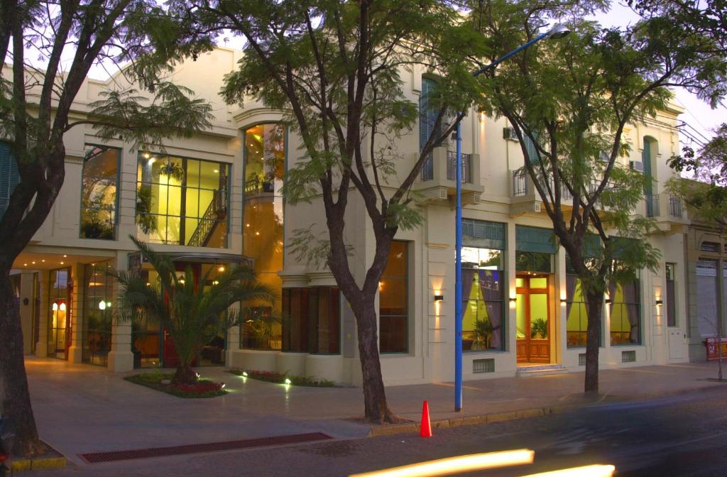 a white building with trees in front of it at Hotel Plaza Rafaela in Rafaela