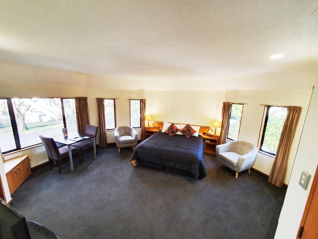 a bedroom with a bed and a desk and chairs at Fitzherbert Castle Motel in Palmerston North