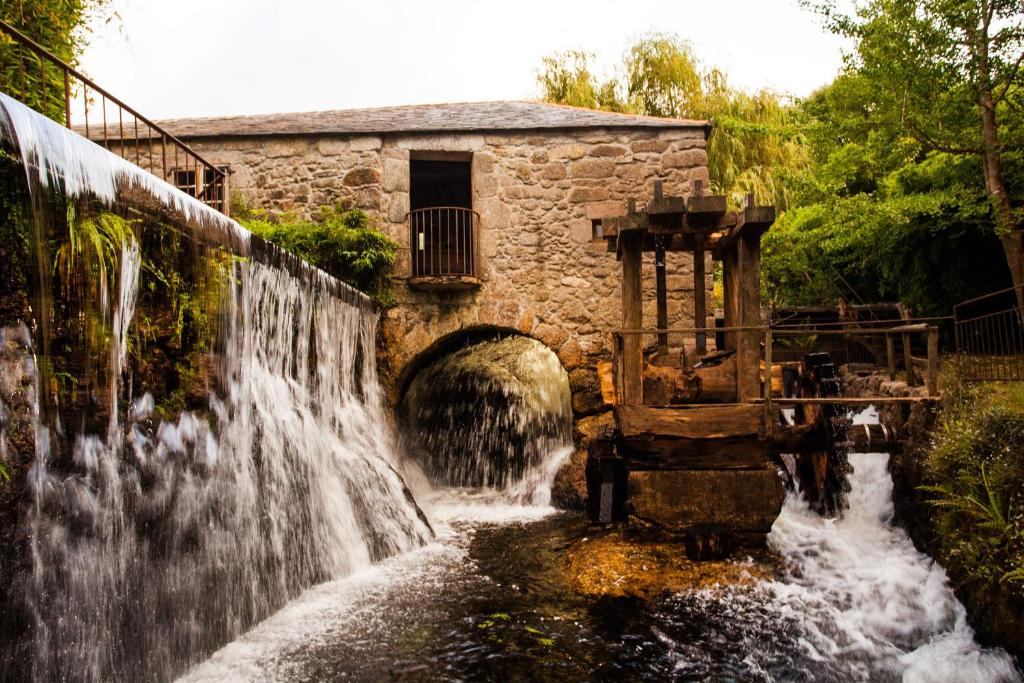 a waterfall in front of a stone building at Finca Galea in Carballido