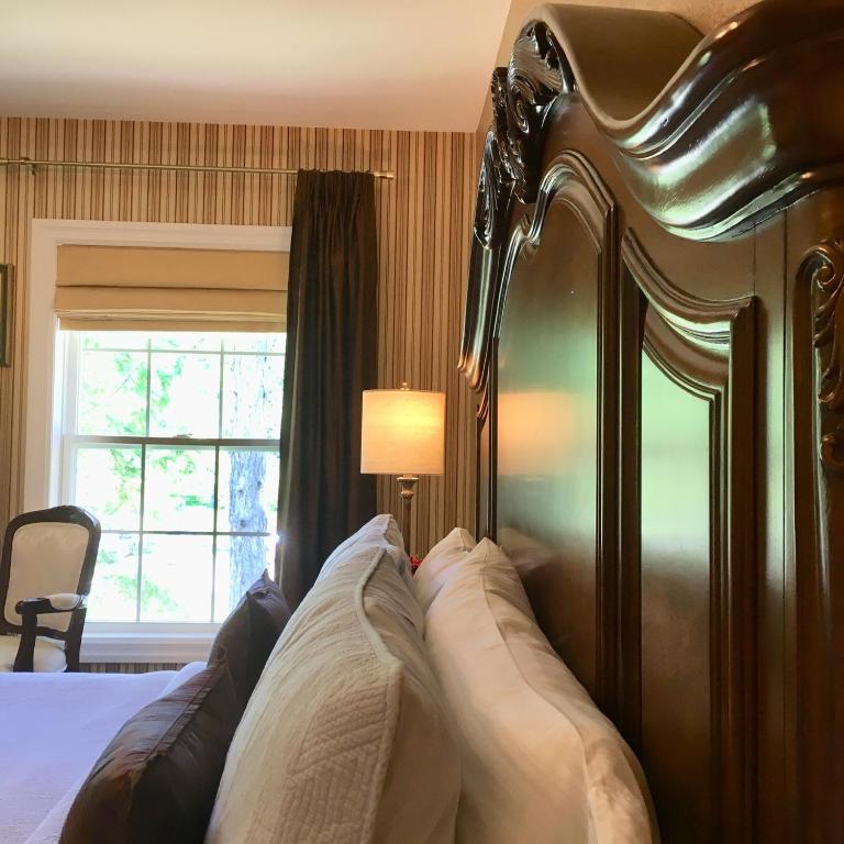 a bedroom with a bed with a wooden headboard and a window at Darlington House Bed and Breakfast in Niagara-on-the-Lake