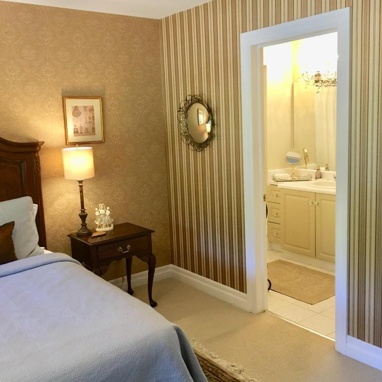 a bedroom with a bed and a bathroom with a sink at Darlington House Bed and Breakfast in Niagara-on-the-Lake