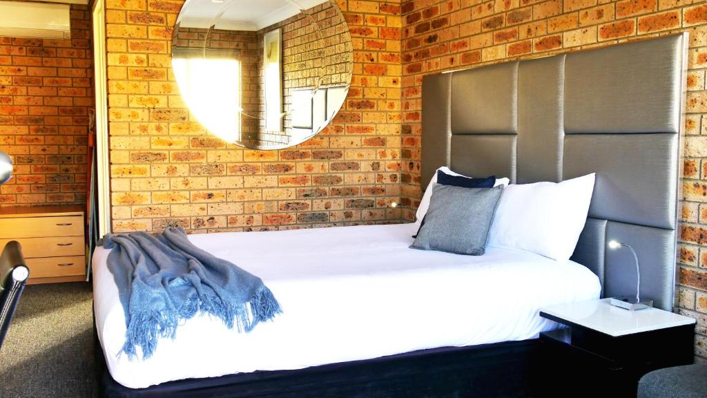 a bedroom with a large bed with a brick wall at Country Capital Motel in Tamworth