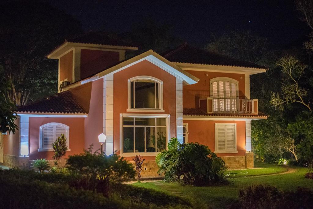 uma casa iluminada à noite em Pousada Quinta dos Pássaros Itaipava em Itaipava