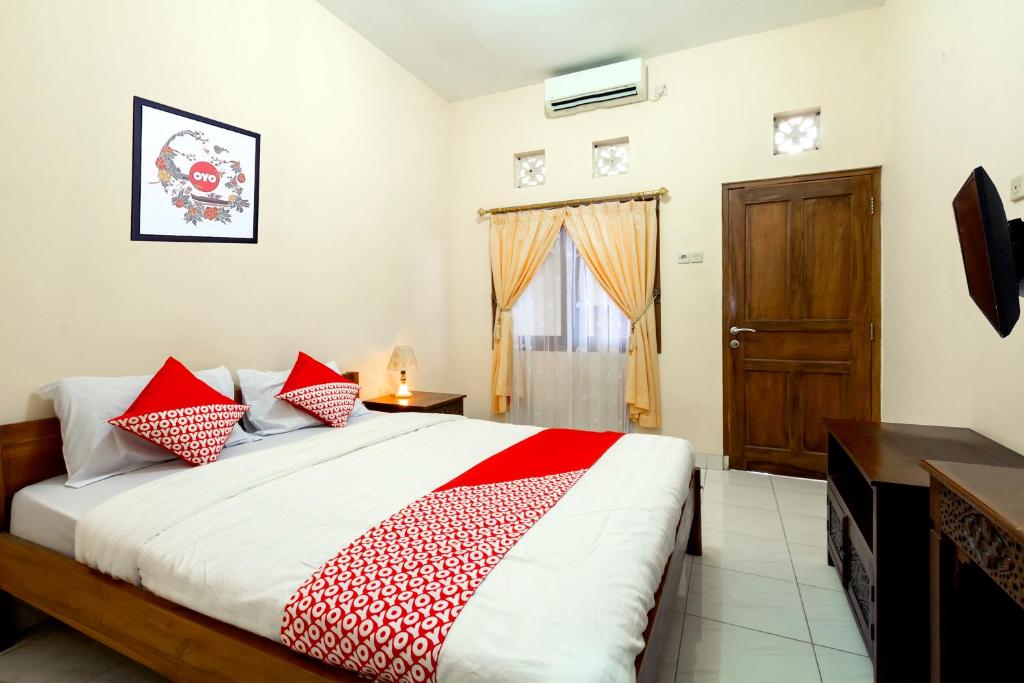 1 dormitorio con 1 cama con almohadas rojas y blancas en Super OYO 1150 Omah Ladrang, en Yogyakarta