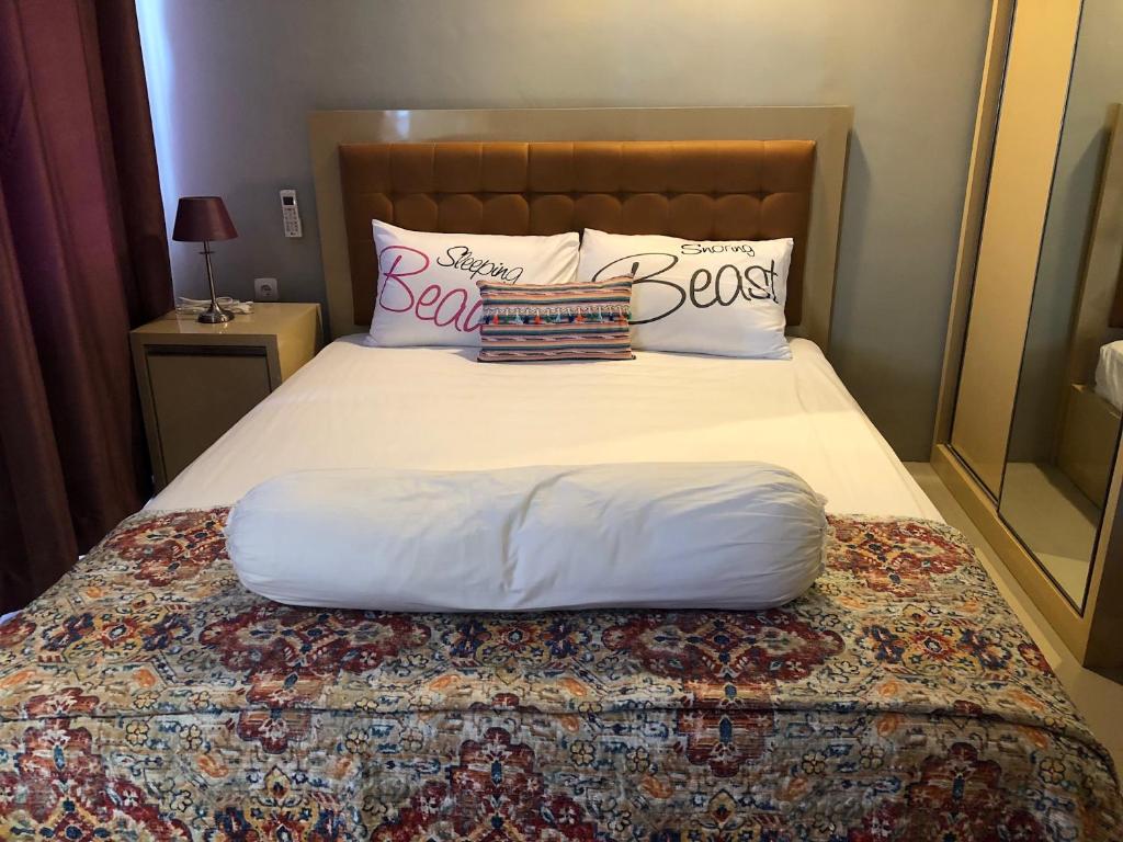 - un lit avec des draps et des oreillers blancs dans l'établissement Ruang Bravia Bogor Icon Hotel, à Bogor