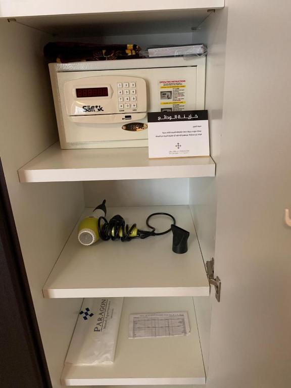 a shelf with a microwave and a box in a refrigerator at Paragon Hotel Apartments in Abu Dhabi