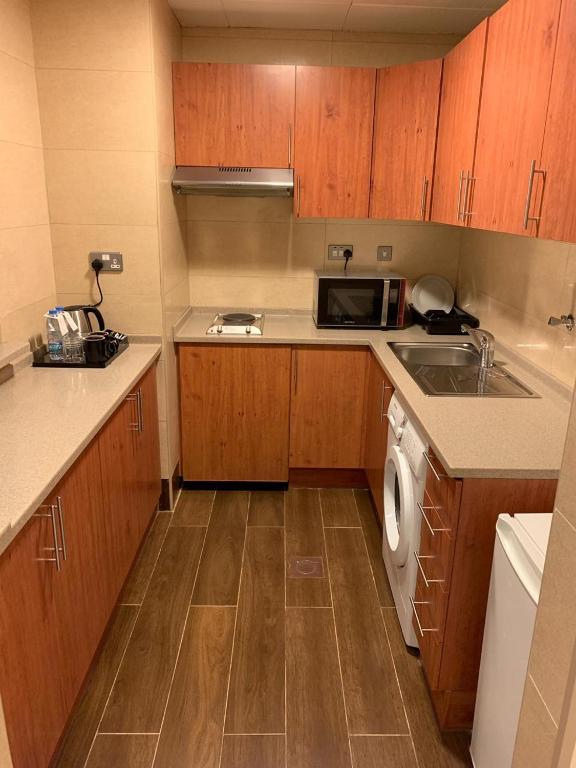 a small kitchen with a sink and a microwave at Paragon Hotel Apartments in Abu Dhabi