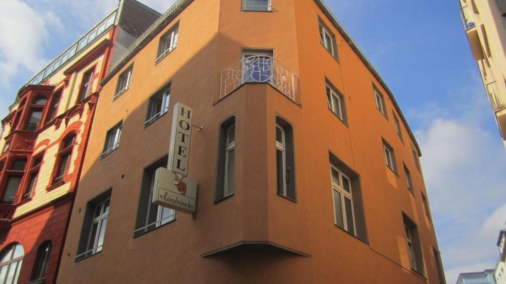 Ein hohes orangenes Gebäude mit einer Uhr drauf. in der Unterkunft Hostel Heinzelmännchen in Köln