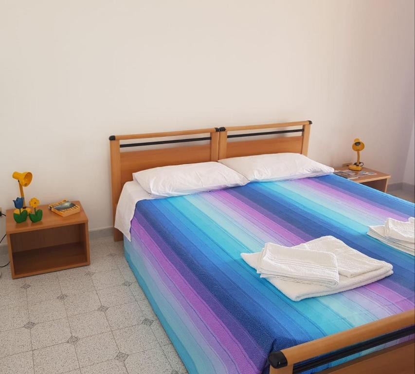 łóżko z kolorowym kocem i dwoma ręcznikami w obiekcie Hotel Residence Il Mulino w mieście Alicudi