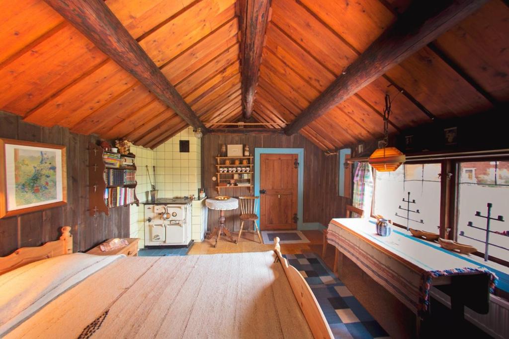 a large room with a wooden ceiling with a table at Egen stuga med delat badrum in Norrtälje