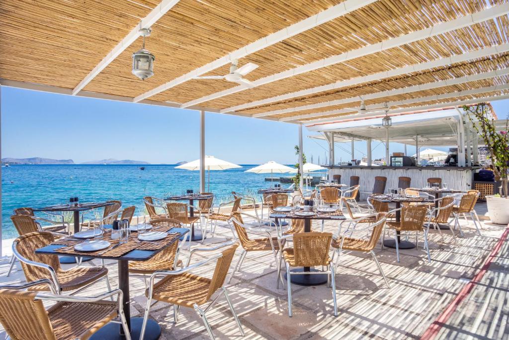 a patio with tables and chairs and the ocean at Spetses Hotel in Spetses