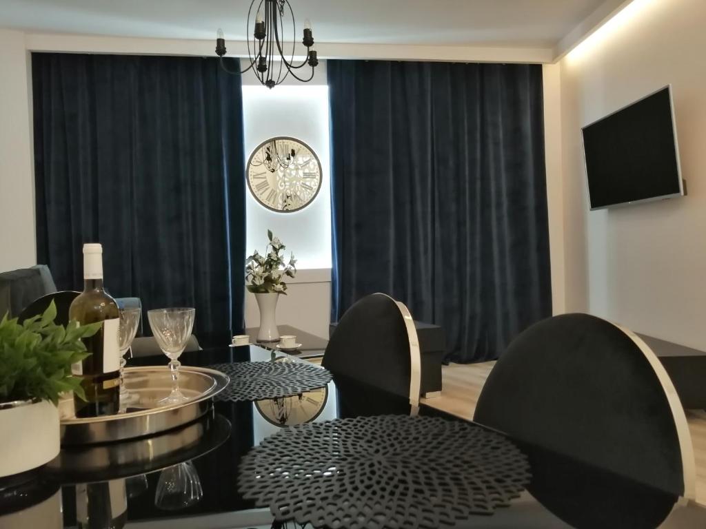 a dining room with a table and chairs and a clock at Time To Relax Apartment in Zielona Góra