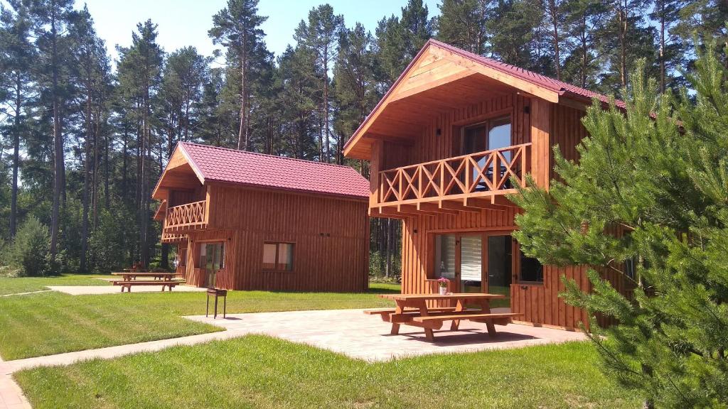 a large wooden cabin with benches in a park at Brīvdienu māja INESE in Bernāti