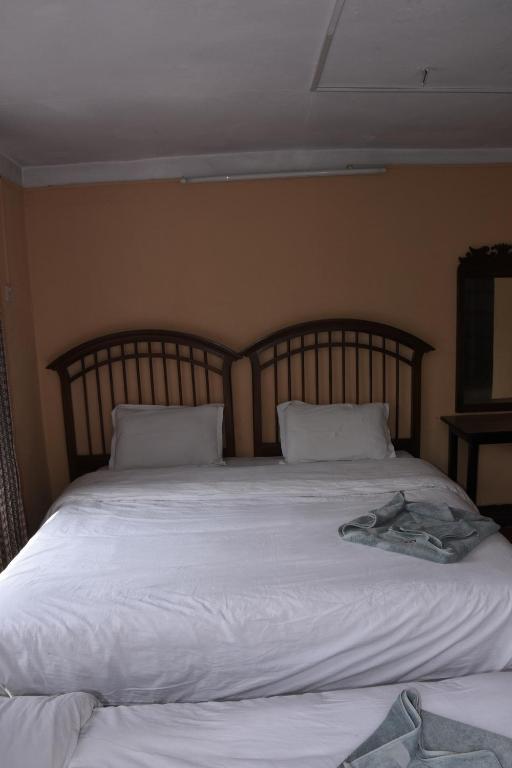 1 cama grande con sábanas y almohadas blancas en Family Peace House, Kathmandu, en Katmandú