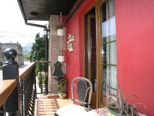 a red building with a chair on a balcony at Posada Trisileja in Cos