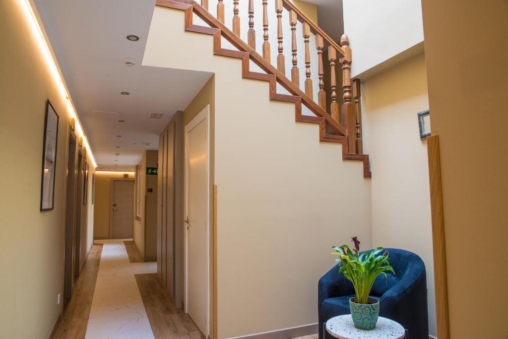 a hallway with a blue chair and stairs at Hotel Gastronómico Torre de Galizano in Galizano