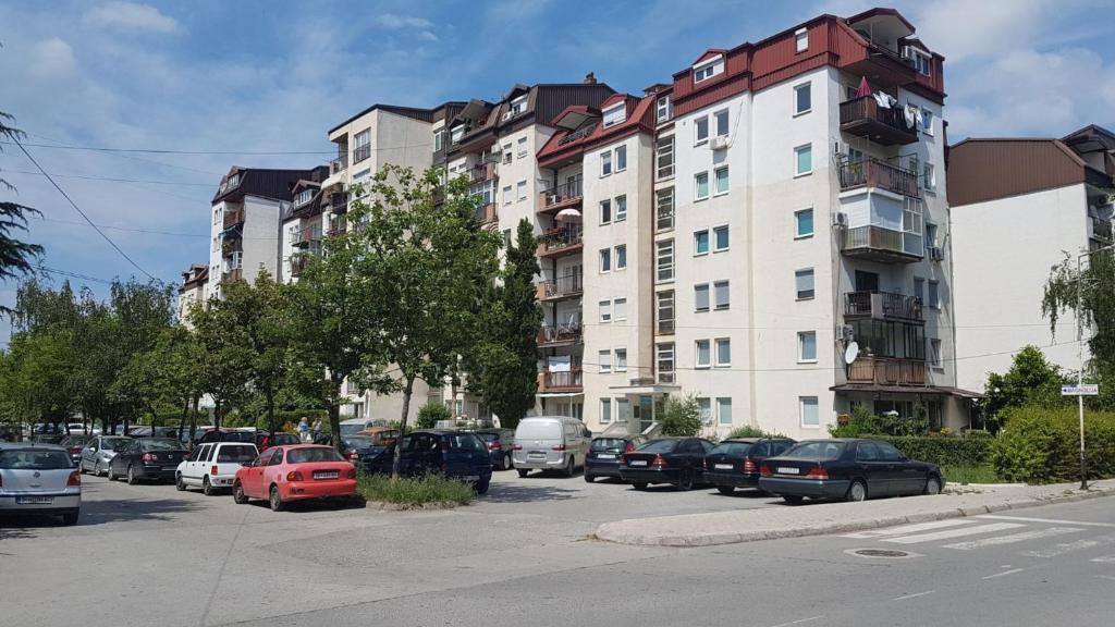 een parkeerplaats met auto's geparkeerd voor een hoog gebouw bij Apartments Magnolija in Ohrid