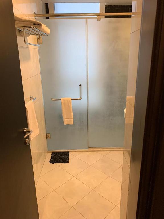 a bathroom with a shower with a glass door at Paragon Hotel Apartments in Abu Dhabi