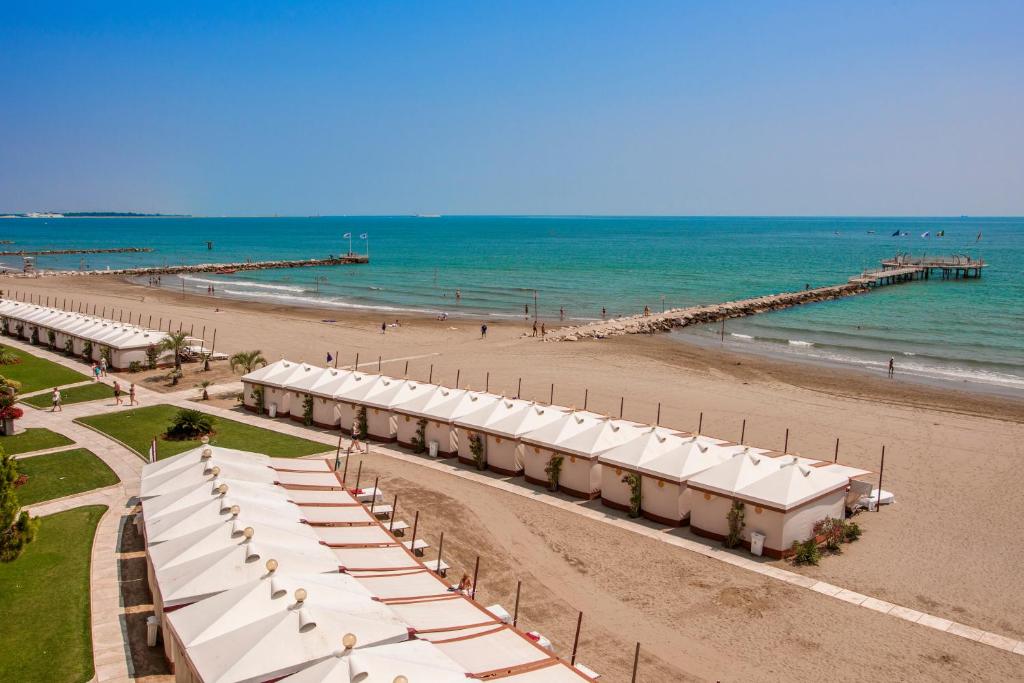 a row of tents on a beach next to the ocean at Hotel Excelsior Venice in Venice-Lido