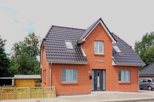 ein kleines orangenes Haus mit schwarzem Dach in der Unterkunft Haus Siegfried in Niebüll